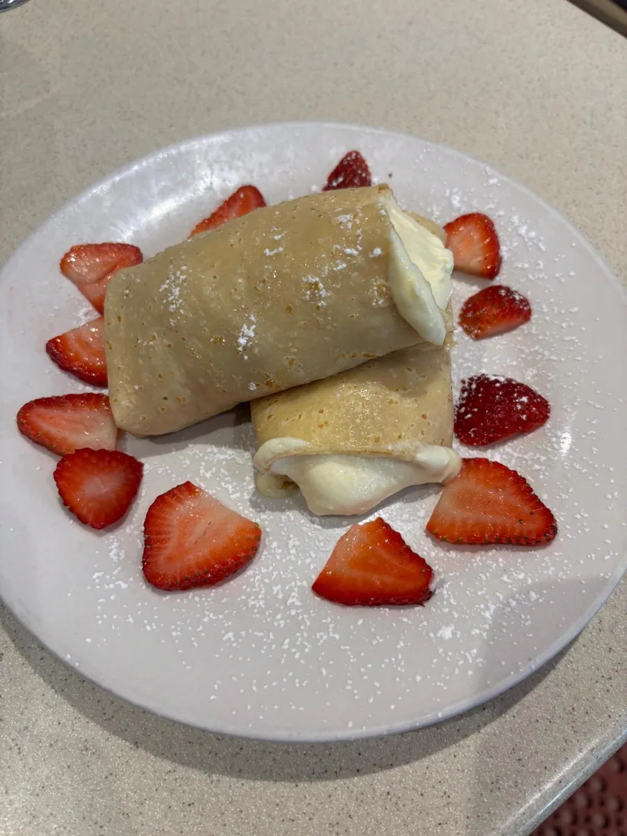 Sweet crêpes with cream and sliced strawberries